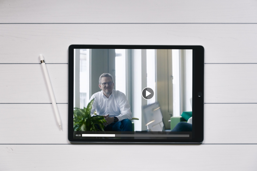 ein Tablet, darauf der Startbildschirm eines Videos mit Connox-Gründer Thilo Haas, vor einem Hintergrund auf weißem Holz